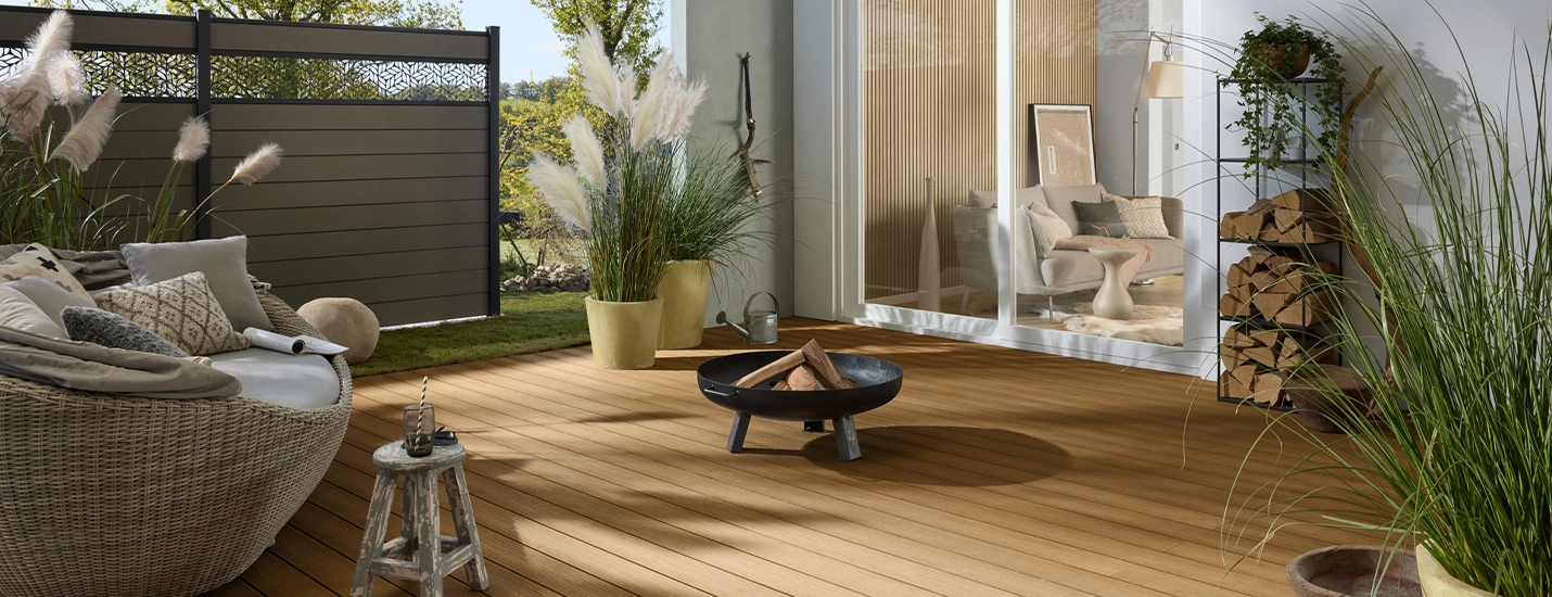 Holzterrasse mit Loungemöbeln und stilvollem Sichtschutzzaun – gemütliche Outdoor-Oase in natürlichem Design.